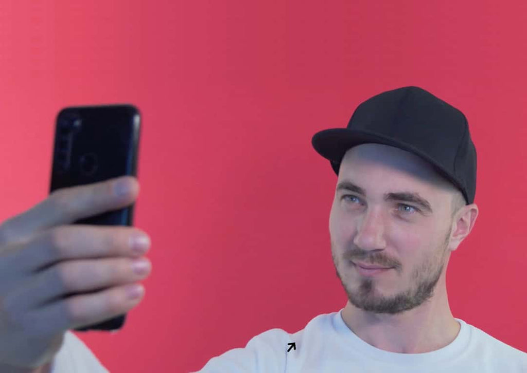 Man wearing a hat while taking a selfie